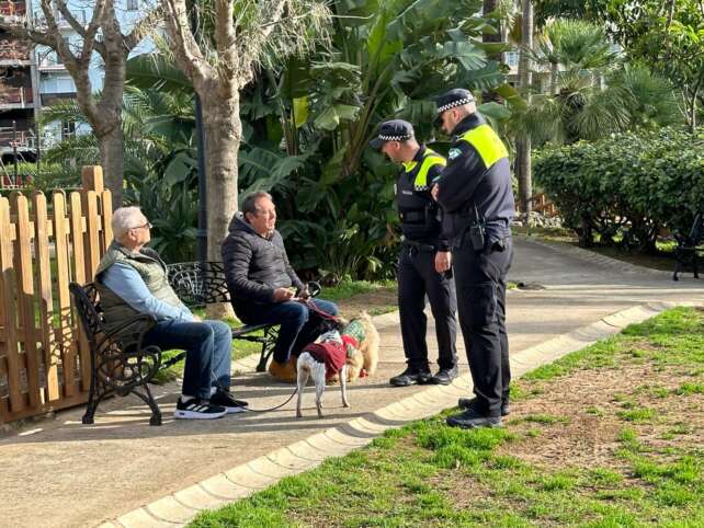 Dos agentes de Policia Local dialogan con unos vecinos en un parque de la ciudad