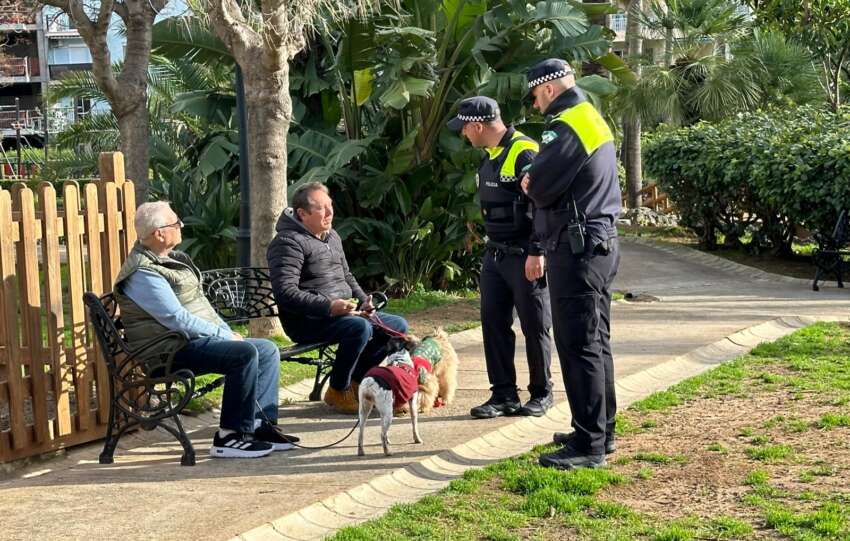 Dos agentes de Policia Local dialogan con unos vecinos en un parque de la ciudad